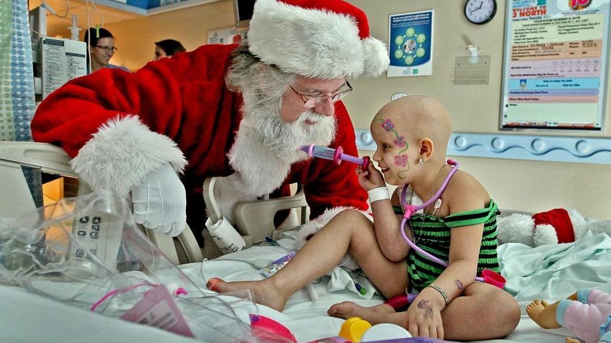 Nicklaus Children's Hospital patient Salette Ruiz, 4, of Hialeah, uses a new toy syringe to give Santa a shot in his beard as he visits her bedside on Thursday December 17, 2015.