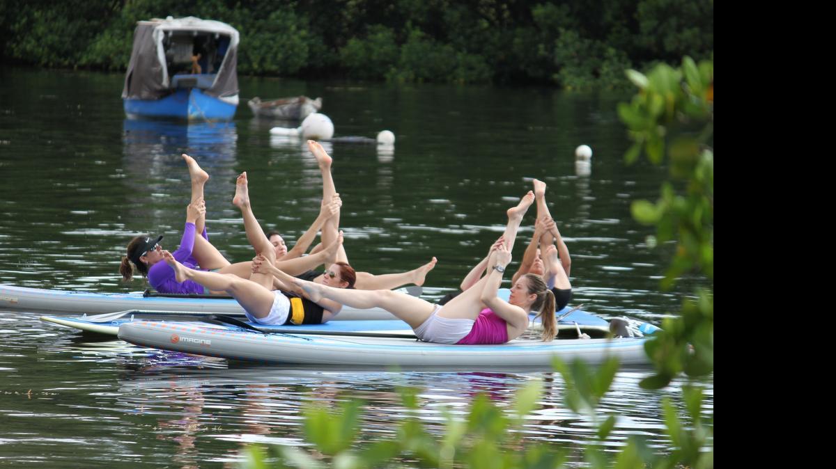 
Students lift their legs to a 45-degree angle in Pilates H2O, a new class in Coconut Grove that blends paddleboarding with Pilates.
