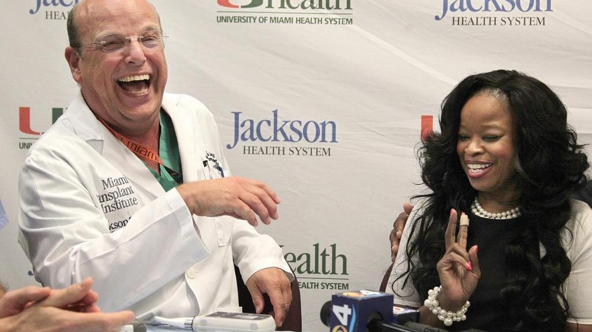 UHealth surgeon Dr. Matthias Loebe, left, breaks into laughter after Erika Carter-Rolle gives him instructions on the prior use of the device's batteries. An assistant principal at M.A. Milam K-8 Center, Carter-Rolle is recovering from a life-saving heart transplant after eight years of "buying time" through the full spectrum of comprehensive care before getting a transplant. Her doctors and husband joined her during a press conference on Monday, Nov. 23, 2015.