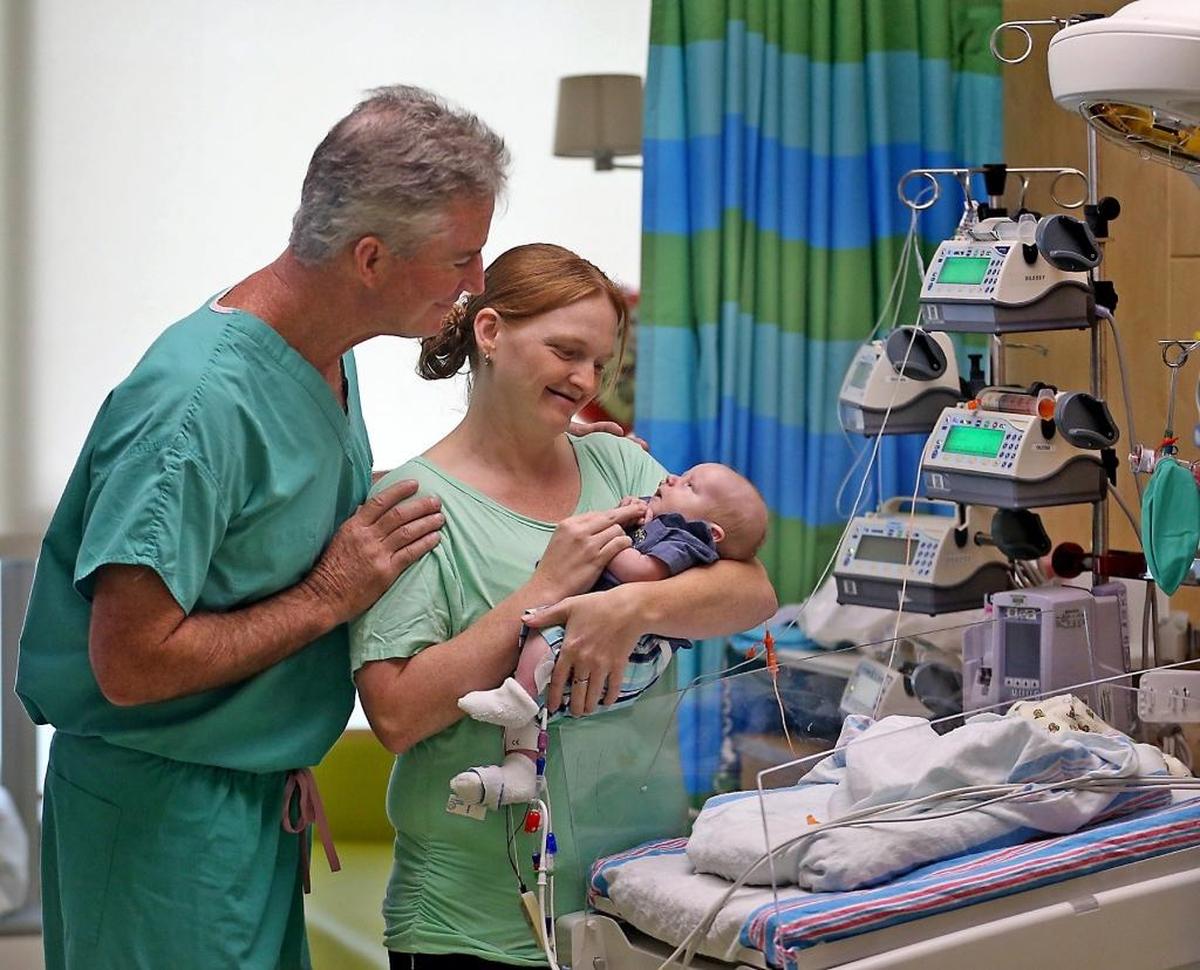 Sarah Lemons cradles her baby, Calvin Taylor, alongside Dr. Redmond P. Burke on Thursday, Aug. 10, 2017. Calvin received life-saving heart surgery at Nicklaus Children’s Hospital by Burke after being deemed inoperable by four high-risk congenital heart transfer hospitals.