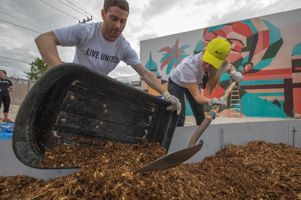 Brett Abess and Taryn Gordon, two United Way volunteers, plant a vegetable garden at the Opa-locka Community Development Center.