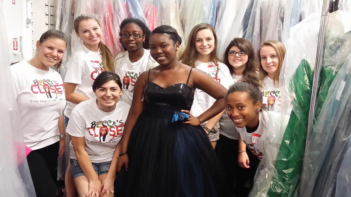 Student volunteers with a customer looking for a prom dress