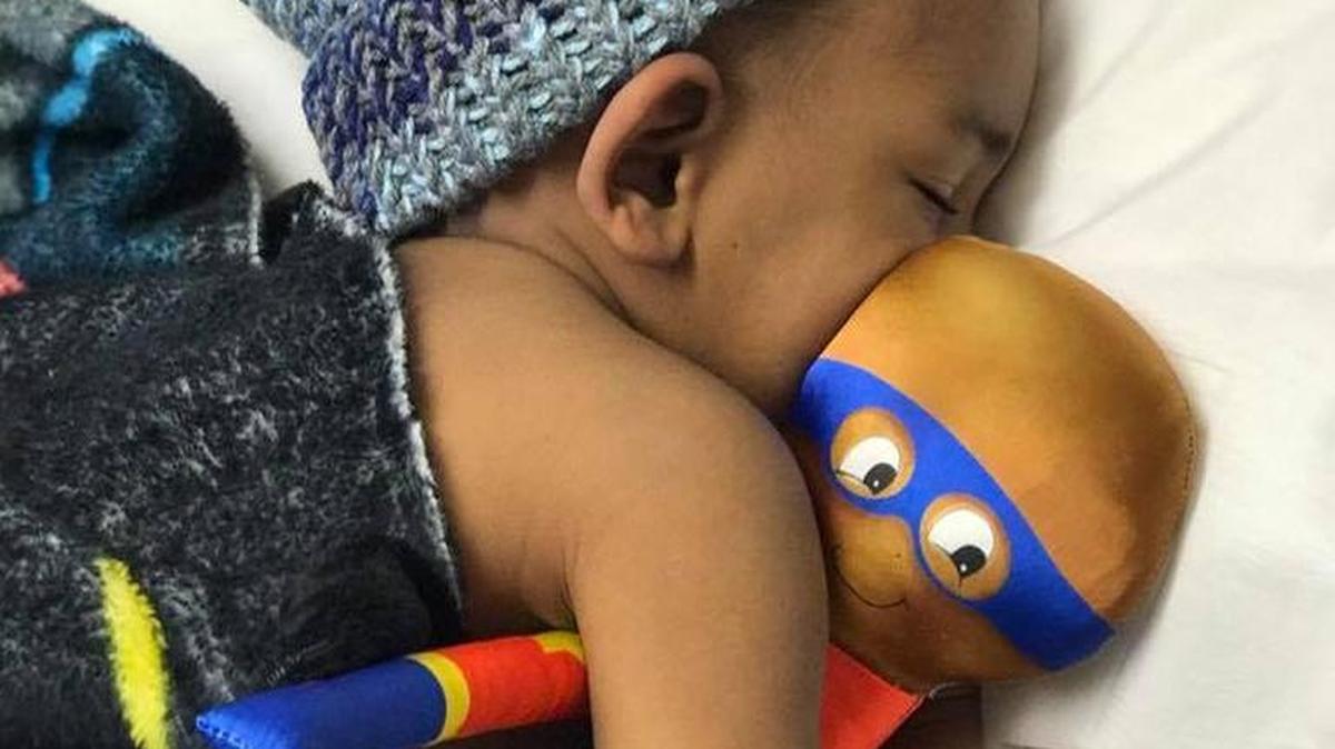 A small cancer patient cuddles her Bee Brave Buddy.