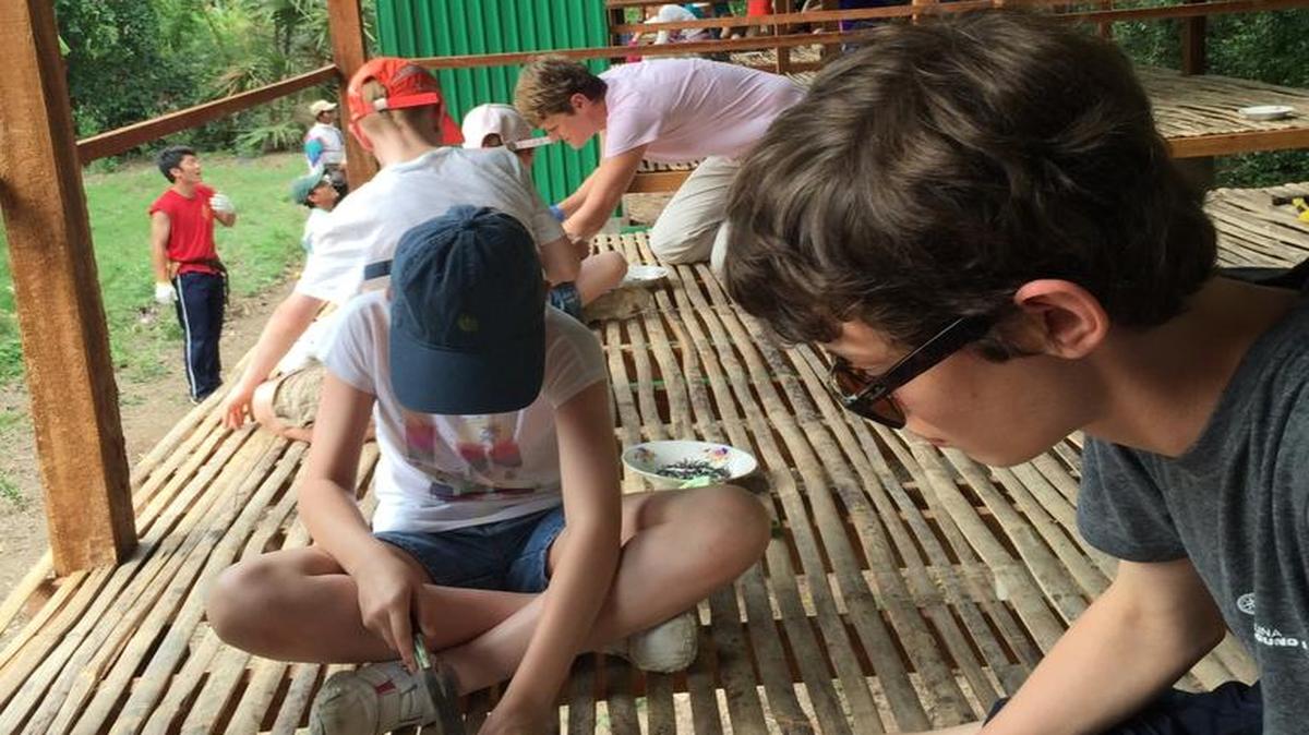 Ethan Hill and team members from Global Builders nailing bamboo floors in new home at Tabitha Cambodia project, Kampong Speu Province, Cambodia, June 23, 2015