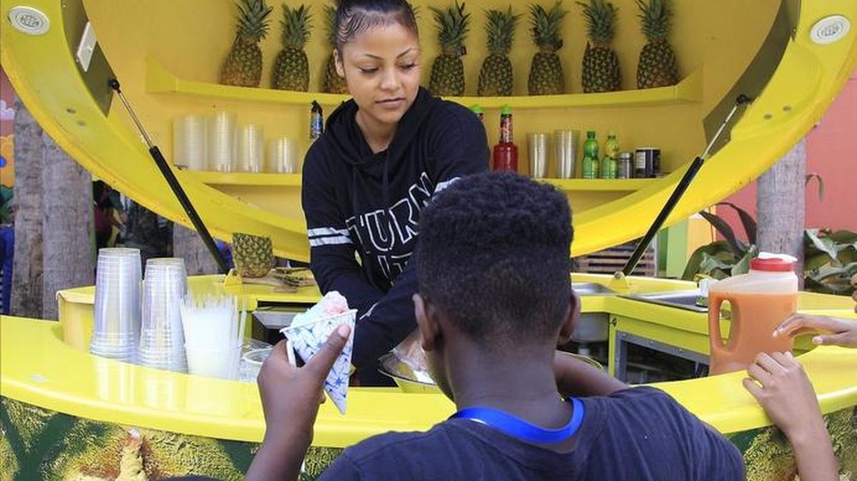 Pineapple Express owner Katherine Hernandez, center, offers a healthy sample of conch salad at the Overtown Youth Center which held its first free Enrichment Festival with live music, food, free haircuts, and other fun activities due to the teacher workday for Miami Dade County Public Schools on Monday, January 23, 2017.