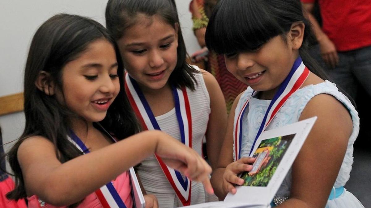 Evelyn Mateo, right, shares her book with fellow new authors Briana Maravilla, left, and Rosario Gomez at the New Authors Ceremony at the Miami Dade College, Homestead Campus on Wednesday, Oct. 26, 2016.