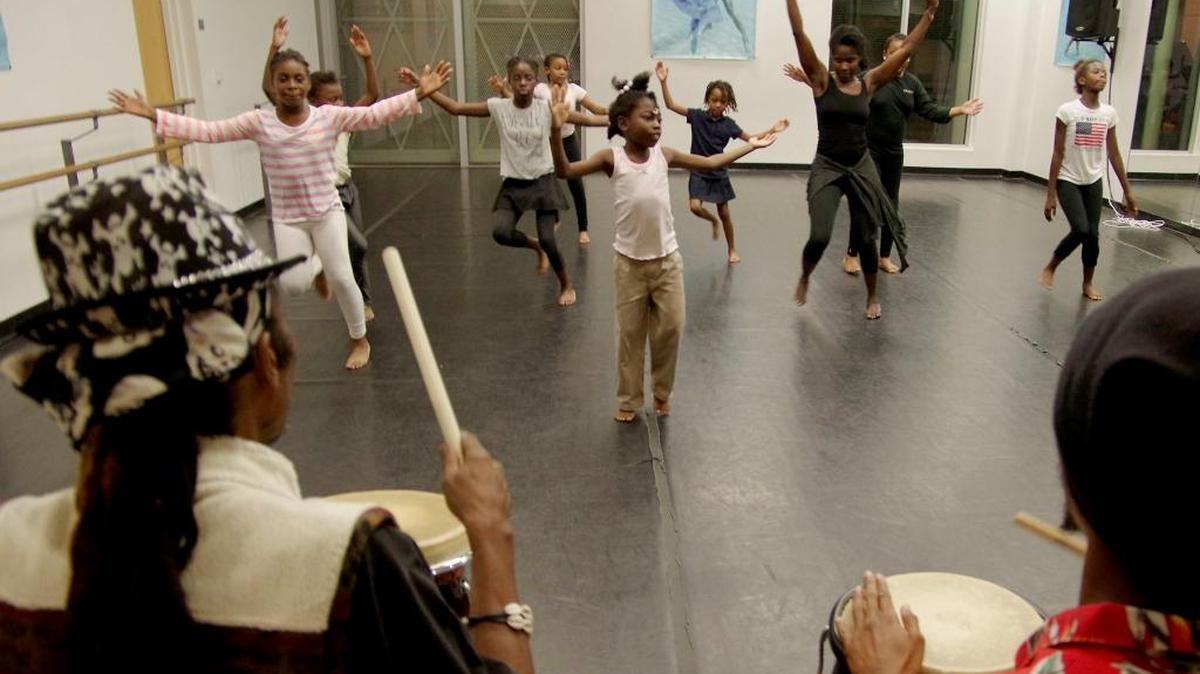 The class dances together in time to the music played by, Samba Maalik (right) and Master drummer Matisou Legba left during a Tradisyon Lakou Lakay dance class at the Little Haiti Culture Center in Miami.
