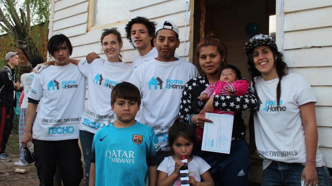 Andrea Pires and Ricardo Juarez and their three children stand in front of the home that Home4Home built for them in Argentina.