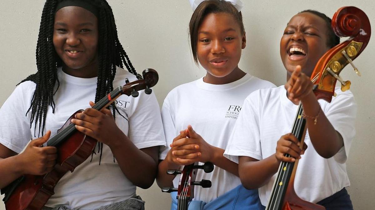 Music student Brian Robb, 12, left, Tiffani Harpp, 10, stand with their instruments during a photo shoot as Nia De Silva, 9, right, breaks into laughter. On Sunday, October 16, 2016 the UM's Frost School of Music held its MusicReach program that pairs UM music students with Miami-Dade school age kids for a mentorship program. Kids learn lessons in teamwork, creativity, leadership and music lessons.