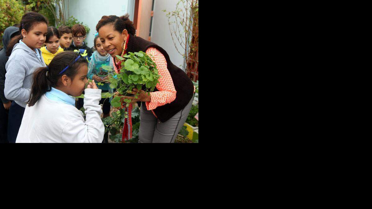 
Eimy Beritez, (left in white shirt) smells a plant held by her teacher Alena Sheriff, (right) in the food forest at Twin Lakes Elemetary. Instead of planting crops in rows horizontally the different layers of the forest are used to plant a variety of food crops.
