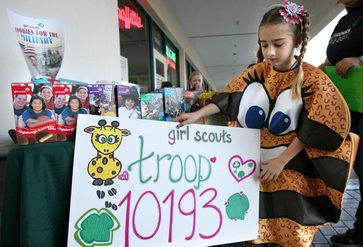 Lexie Galletta, 7, of Girl Scout Brownie Troop 10193, dresses like a Samoa cookie while preparing a sales booth in 2012.