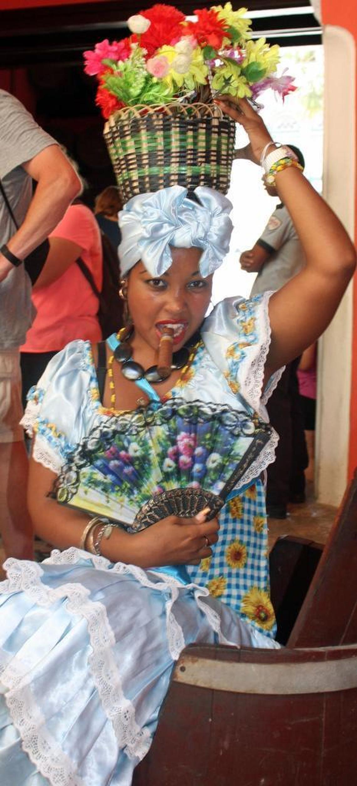 At the Rum Museum in Havana, a woman in traditional Cuban dress poses for a photo, then asks the tourist for a tip.