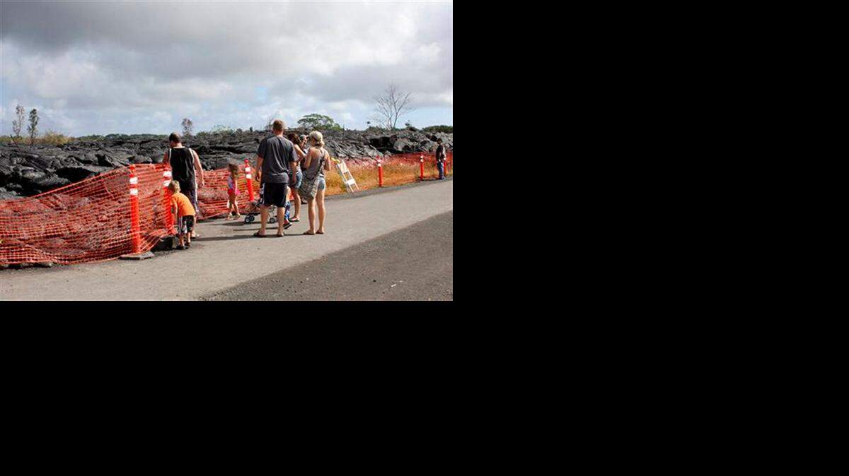 
Visitors view a section of cooled lava from lava flow that began on June 27 as it approaches a shopping center in Pahoa, Hawaii, on Dec. 19. 
