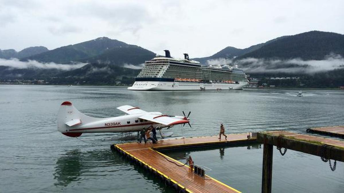 
A sea plane is at a dock as a cruise ship is anchored in the background in Juneau, Alaska. Juneau is only accessible by boat or plane. 
