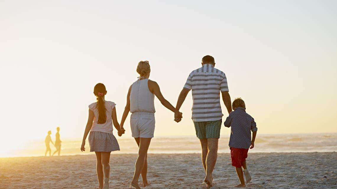 Full length view of parents with children holding hands while walking on beach