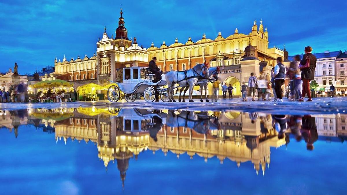 A rain puddle reflects the floodlit charm of Cloth Hall, one of several noteworthy buildings on Kraków's Main Market Square.