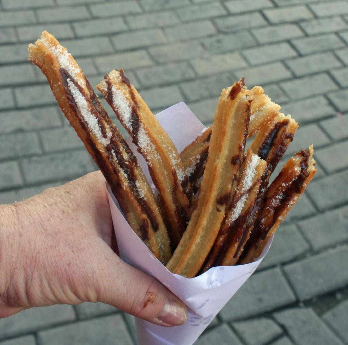 Visitors on a food-and-beverage tour of Havana sample churros sold by a street vendor.