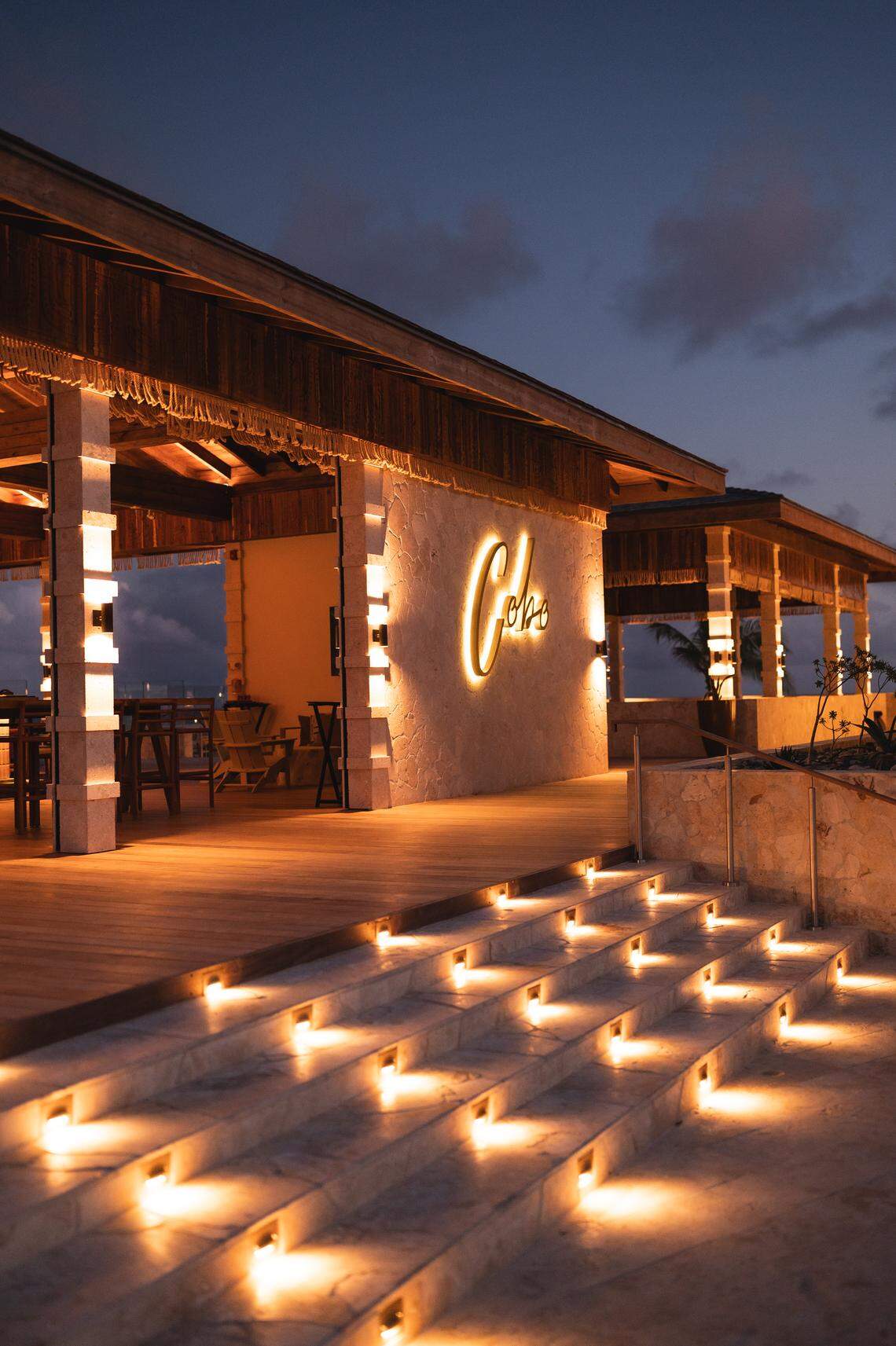 Cobo Bar & Grill glows at dusk, welcoming guests with ocean views and a menu of Latin-inspired seafood dishes.