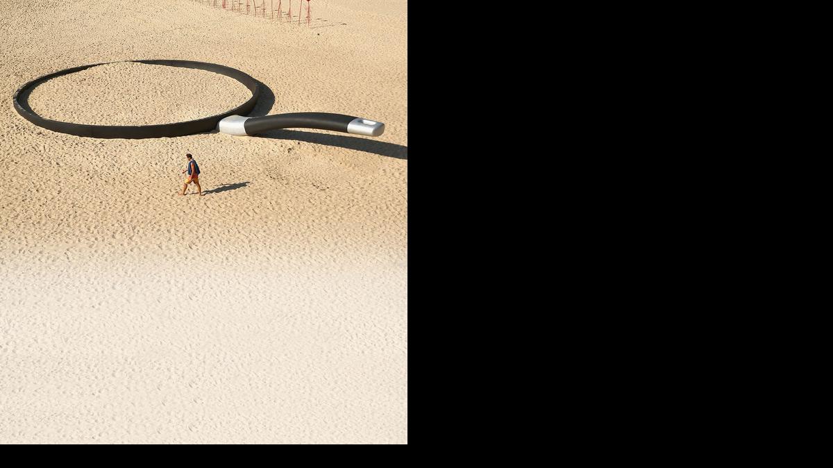 
A person walks past 'We're fryin' out here' by Andrew Hankin during the 2014 Sculptures by the Sea exhibition at Tamarama Beach on in Sydney, Australia. 
