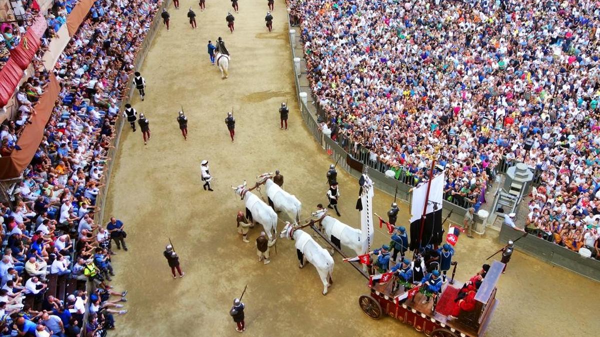 The crowd looks on as an oxen cart pulls the Palio banner through Siena’s main square.