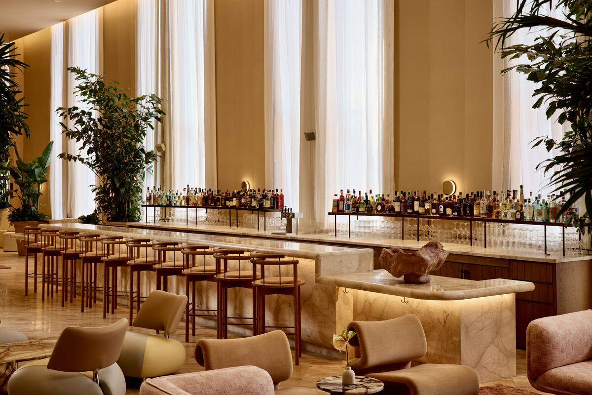 Elegant, modern bar with warm tones and lush greenery at the Shelborne.