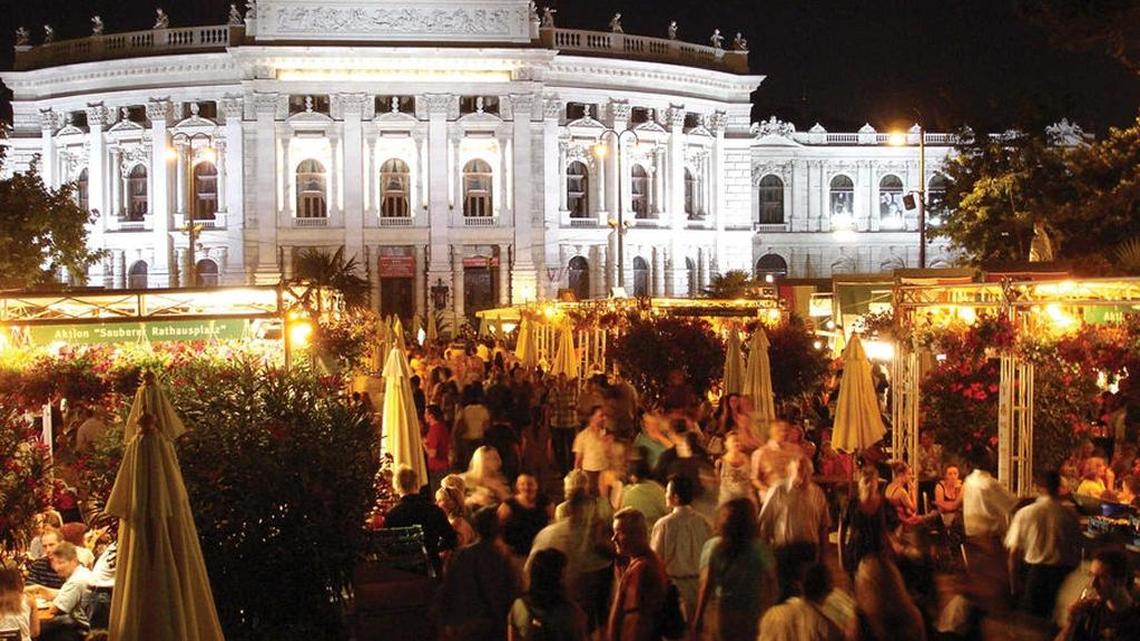 On a summer evening in Vienna, people drink, munch, and mingle before the outdoor opera begins.