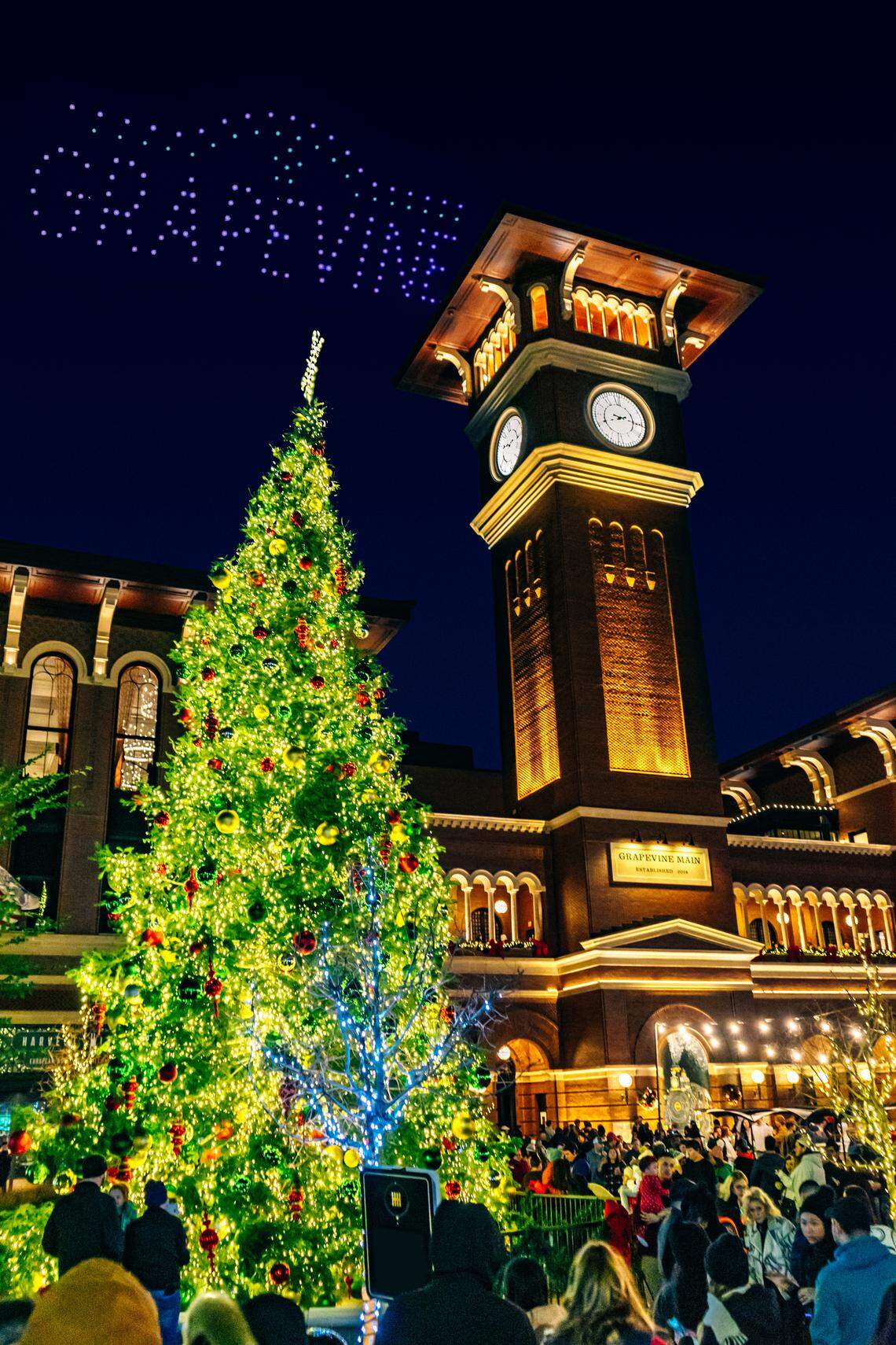 A festive crowd gathers to watch the drone show under the towering Christmas tree at Grapevine Main.