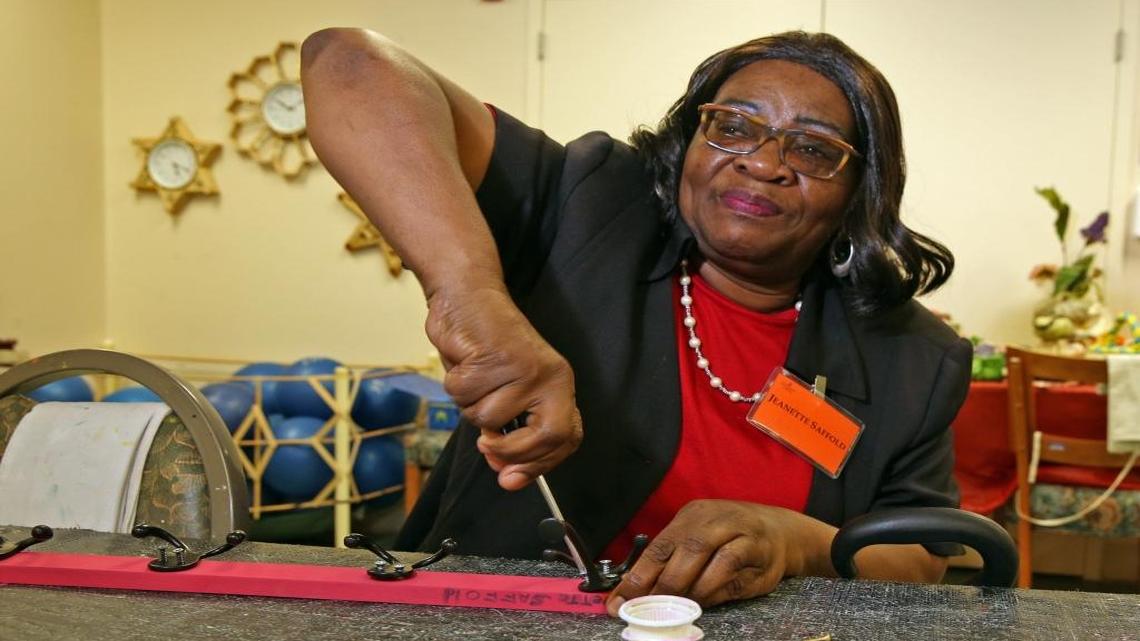Jeanette Saffold, 58, a blind grandmother who was recently homeless, and who is seeking furniture for her new but empty apartment, works on a hat rack at the Miami Lighthouse for the Blind.