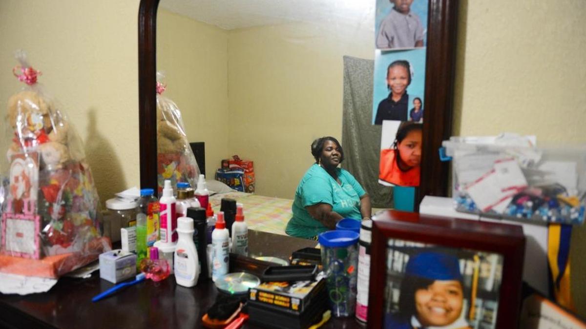 Tehsia Green sits on her bed in her apartment in Miami. Her daughter Precious Jackson’s ashes sit on the dresser.