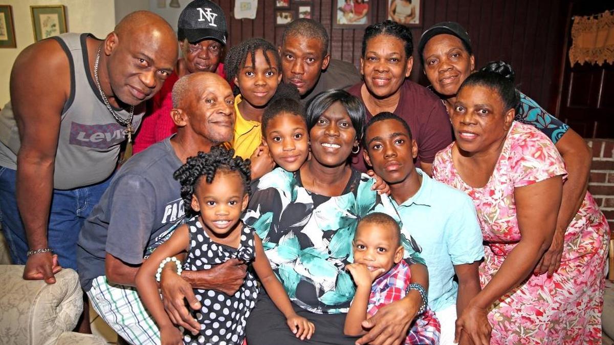 Adrienne Grant-Simpson, seated at center, with her children and family in her Sunrise home on Nov. 30. Adrienne Grant-Simpson, 40, has Stage 4 breast cancer with metastases to the lung and now the brain.