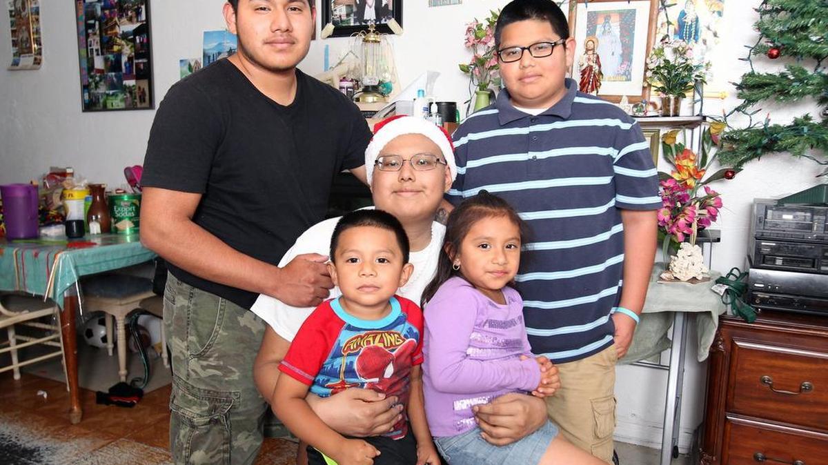 José Mateo, seated, wearing a Santa hat, is surrounded by his siblings, Clementino, 17, left, Ismael, 12, right, and Angel, 3, and Marina, 5, sitting on his lap. Mateo suffers from an acute form of leukemia known as ALL.