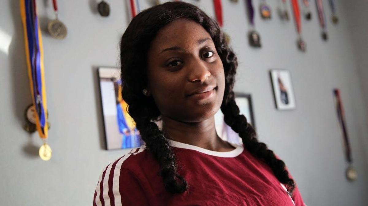 Quanisha Hepburn- 18 years old, stands proudly in front of her many medals that she won as a cheerleader. She was an innocent bystander who was shot earlier this year but somehow managed to graduate from high school and now needs a laptop and a car to help her find a job.