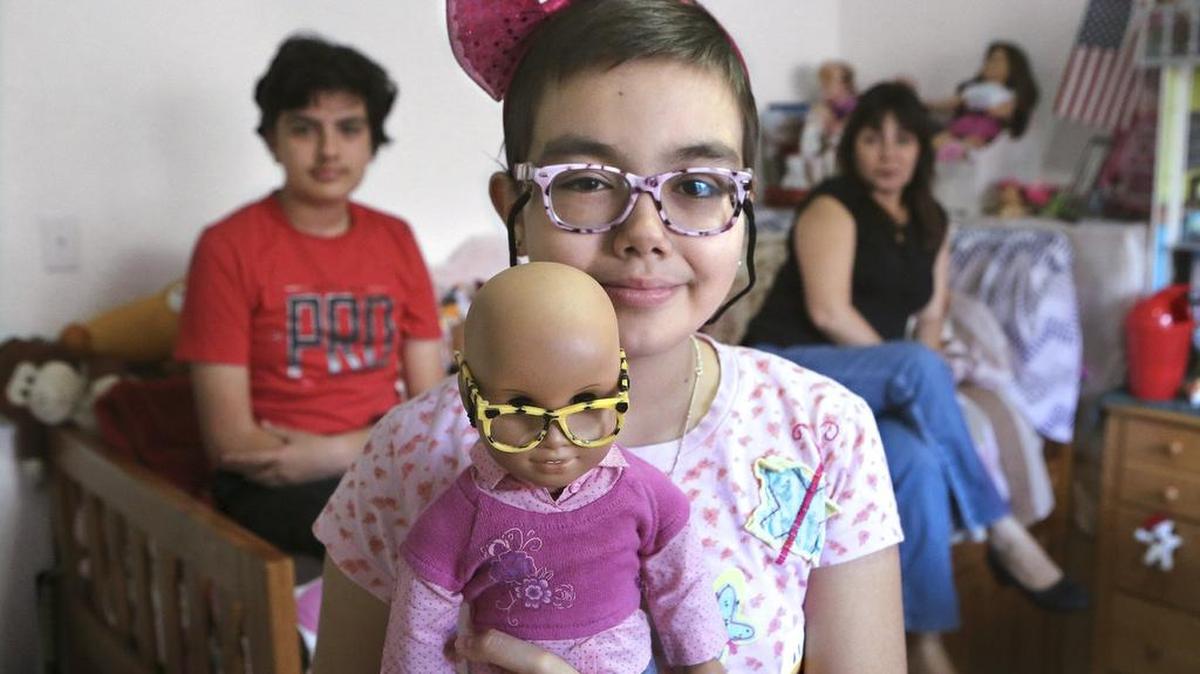 Melodie Ruiz, 12, holds the American Girl doll she was given after she lost her hair due to chemotherapy. Melodie was diagnosed with leukemia at age 11 and still receives chemotherapy. Her mother, Patricia Tannert, right, raises Melodie and brother Patrick Ruiz, 14, left, in a two-bedroom rental apartment in Kendall. The family needs a new laptop so Melodie doesn’t have to do her homework on a cell phone.