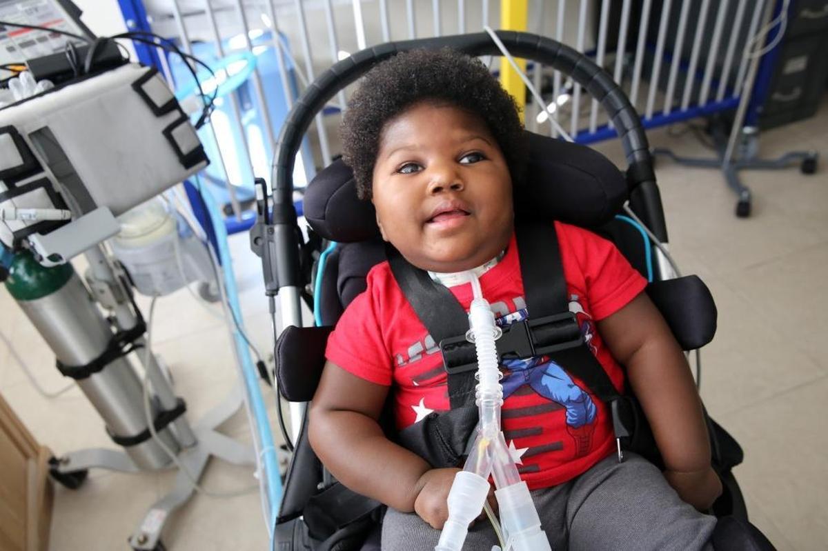 Seventeen-month-old Samuel Augustine sits in a wheelchair that is now too small for him. Samuel was born prematurely with microcephaly and remains confined mostly to his crib in a one-room studio he shares with his parents.