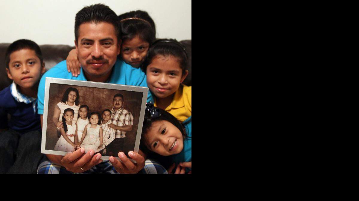 
Lucas Ajtum remembers the good time while he holds the family photo of him, his now-deceased wife, Veronica, and their children: Leonardo, 7, left, Margarita, 8, Francisca, 6, right, and Bani, 4, lower right corner. They are all struggling with their loss this holiday season. Lucas Ajtum is a single dad trying to raise his children and hoping to have gifts for them this holiday season. The Ajtum family is photographed in their Florida City home.
