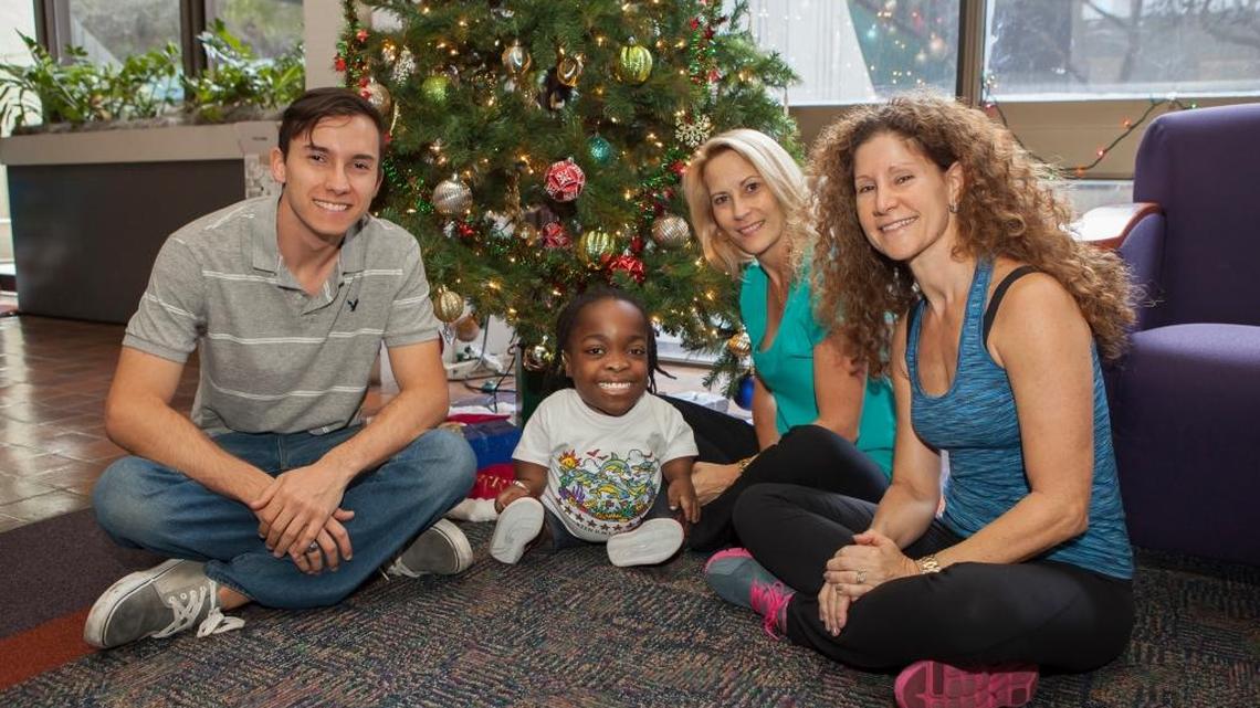 Wish Book contributors Micheal Perez and his mother, Maria Perez and Leda L. Falero sit with Wildine Aumoithe after giving her a laptop and printer.