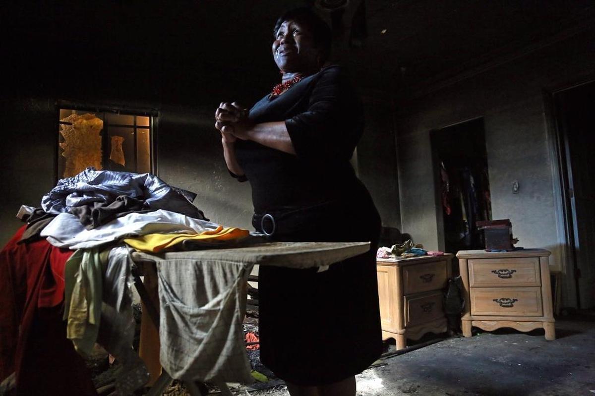 Melissa Allen, a grandmother of three young children, needs some financial help after a fire burned her home and destroyed most of her belongings. She clasps her hands as she thanks God for saving her and her grandchildren inside her fire-damaged bedroom on Sunday, Dec. 3, 2017.