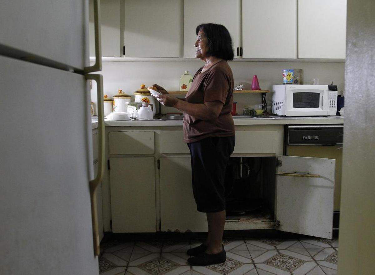 Norma Minsal’s caregiver, Augustina Anduray, 76, stands inside her that is in dire in need of repair.