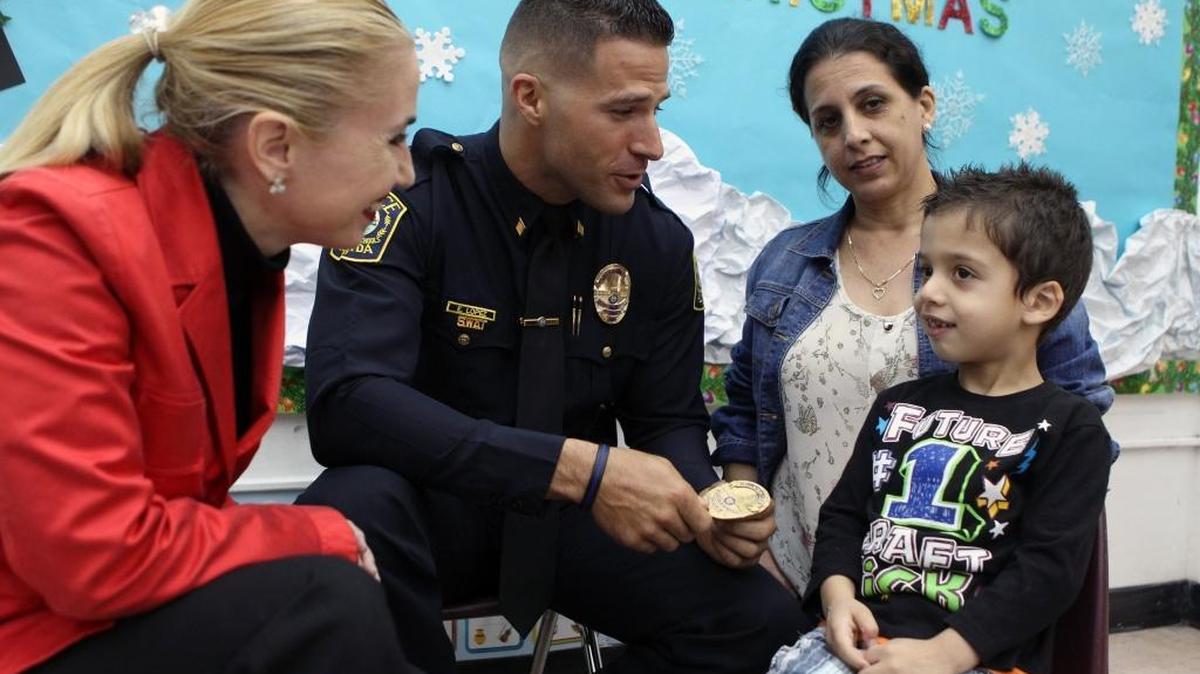 Yamila Carballo, left, director of the English Center, and Commander Edwin López of the Miami-Dade Schools Police Department, with Robert Docina and his mother, Ismary Rey, in the center’s childcare center.