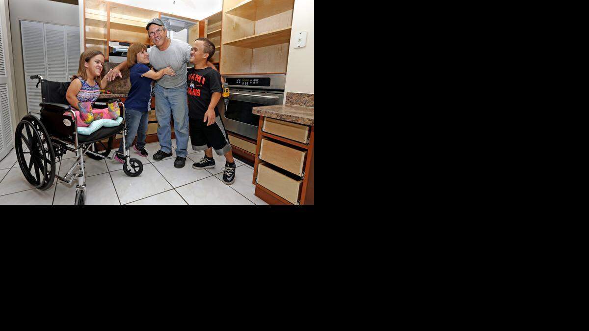 
Carpenter Carlos Diaz gets a hug from Lissette Ference and her children Zach, 17, and Alannah, 13. The Ference family’s kitchen cabinets were lowered with help from Wish Book readers.
