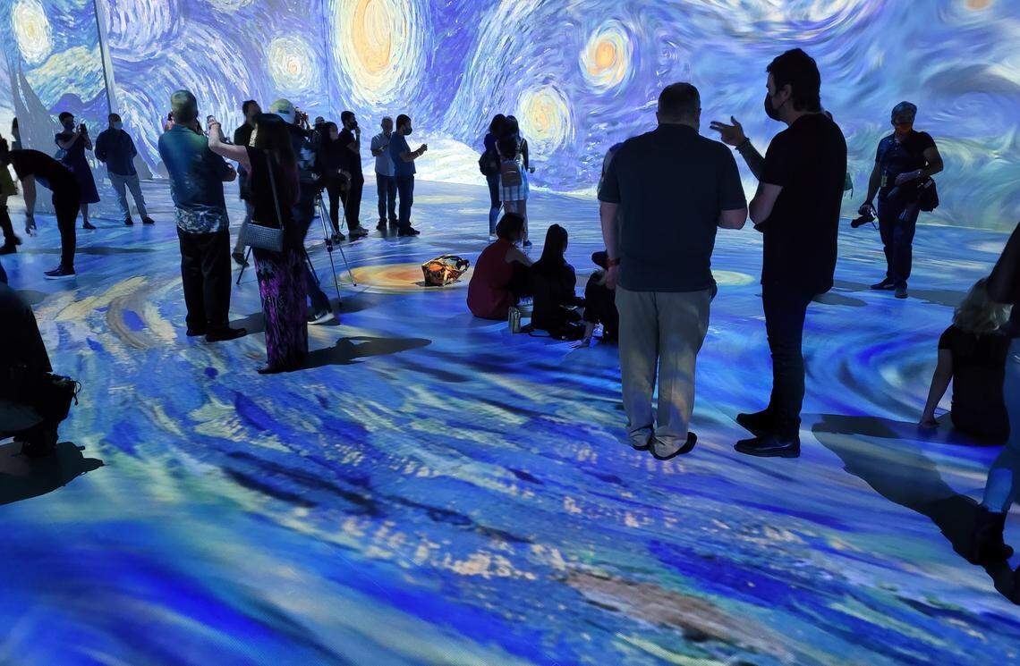 Guests stand inside a projection of Van Gogh masterpiece “The Starry Night” at “Beyond Van Gogh” exhibit at Ice Palace Studios in Miami.