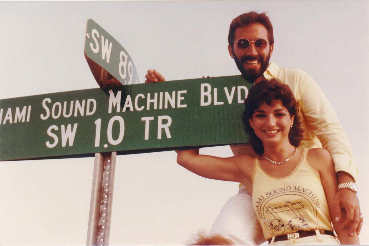Gloria and Emilio Estefan, circa 1985, posing with SW 10th Terrace sign, after the street had be re-named: Miami Sound Machine Blvd.
