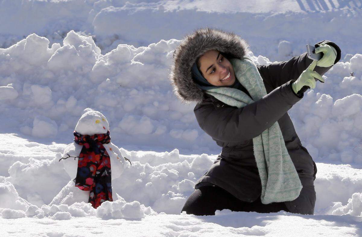 DePaul University student Alaa Hejazi, from Riyadh, Saudi Arabia, shoots a selfie with her very first snowman Monday, Feb. 2, 2015, in Chicago's Millennium Park. The National Weather Service said that the 19.3 inches of snow in Chicago was the fifth highest snowfall total since records started being kept in the late 1800s. (AP Photo/Charles Rex Arbogast)