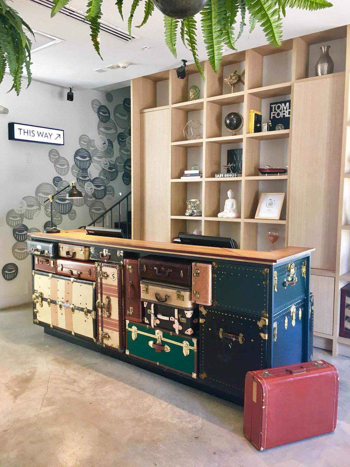 A travel-inspired reception desk meets travelers along with mural work by Miami artist AholSniffsGlue.