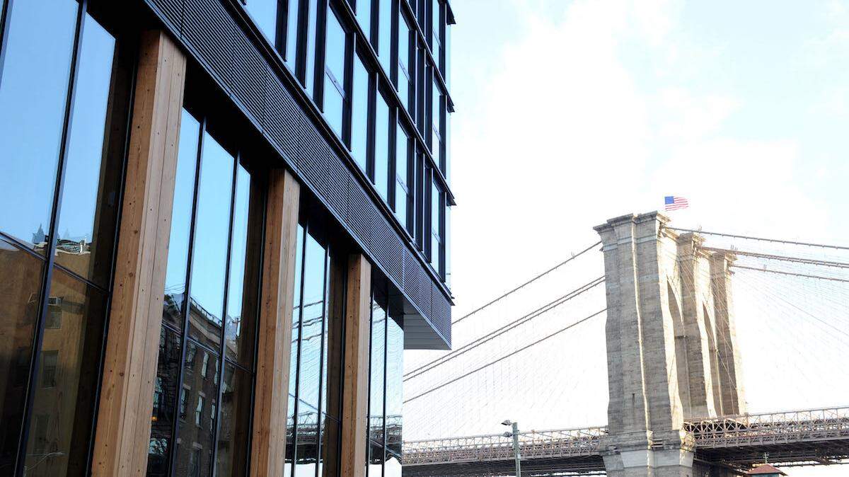 The exterior of 1 Hotel Brooklyn Bridge at the foot of its namesake landmark. Photo by Craig Barritt/Getty Images for 1 Hotel Brooklyn Bridge.