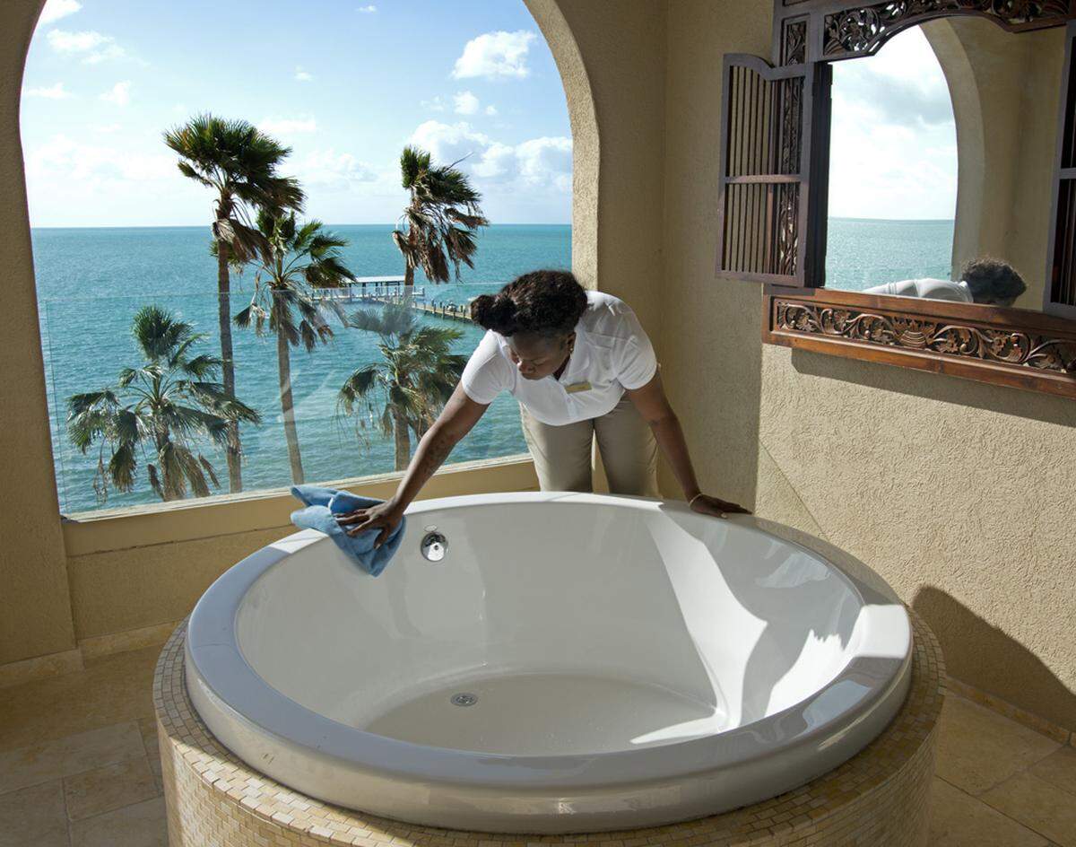 Cheeca Lodge Resort &amp; Spa housekeeper Drimonde Gaspard dusts a guest room's outside bathtub. (Andy Newman/Florida Keys News Bureau via AP)