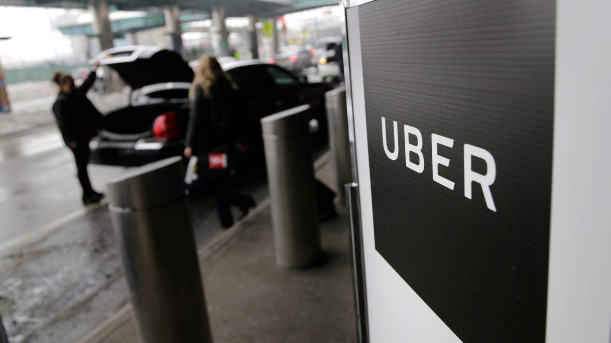 In this March 15, 2017 file photo, a sign marks a pick-up point for the Uber car service at LaGuardia Airport in New York. Ride-hailing giant Uber has reported another multimillion dollar loss even as its revenues grow. The San Francisco-based company said Thursday, June 1, 2017, that its losses in the first quarter narrowed to $708 million from $991 million in the previous three-month period. (AP Photo/Seth Wenig, File)