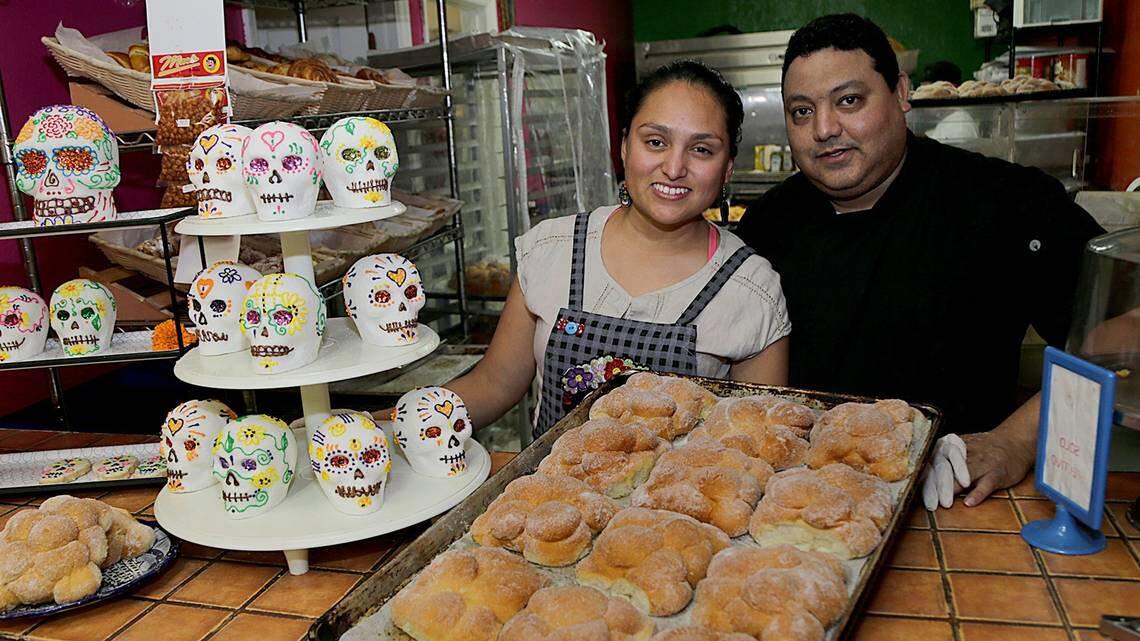 Jocelyn Mendoza and Jaime Reynoso, owners of La Panaderia bakery located inside the Mi Rinconcito Mexicano restaurant, in Little Havana, display a tray of pan de los muertos.
