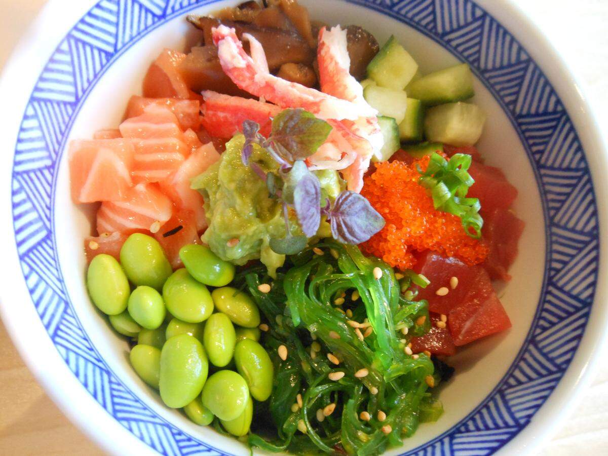 Raw salmon and tuna bowl with seaweed, cucumber, crab, edamame, scallions and tobiko (flying fish roe) topped with mashed avocado.