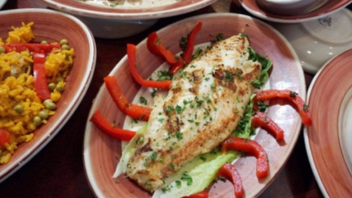 Grilled snapper surrounded by arroz con pollo and palomilla at Islas Canarias. Photo: Chuck Fadely